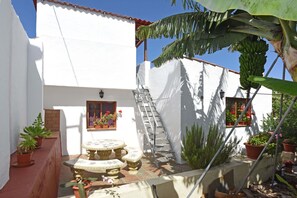 A white building with a tiled roof, a set of outdoor stairs, and potted plants. - Cozy house with garden and sea views (Tazacorte)