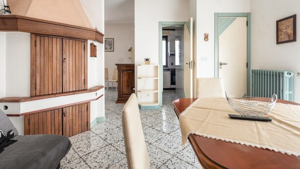 Ett hotellrum med en säng, ett träskåp, ett matbord och ett köksutrymme som syns genom en öppen dörr.