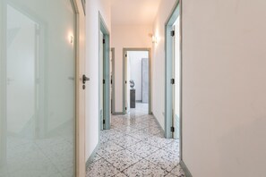 A corridor with a tiled floor, doors on both sides, and a light fixture on the wall. - Holiday Home - Matino (Matino)