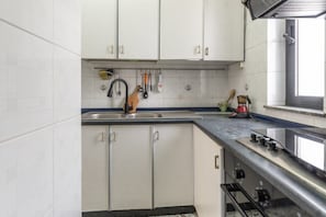 A kitchen with white cabinets, a stainless steel sink, and a stove. - Holiday Home - Matino (Matino)