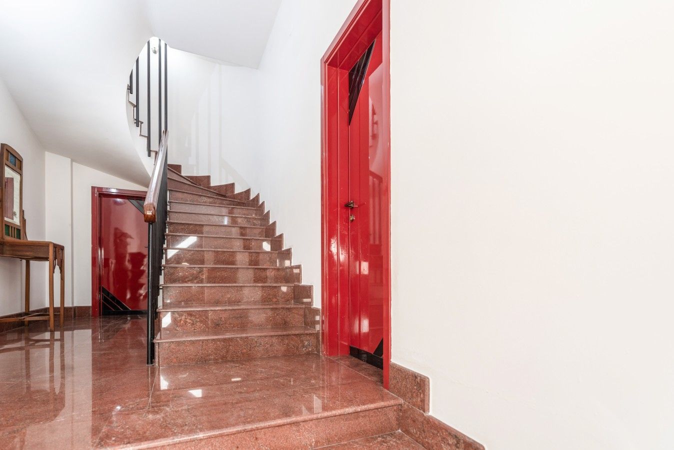 Una scala con un pavimento in marmo lucido che conduce a una porta rossa.