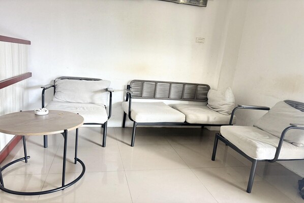 Un espace salon comprenant une table ronde, deux fauteuils et un canapé.