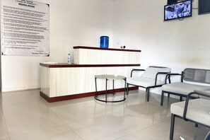 A reception area with a counter, chairs, and a television mounted on the wall. - Cozy Solo Room at Medina House (Banda Aceh)