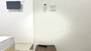 A room with a bed, a small table, a wall-mounted TV, and a thermostat. - Cozy Solo Room at Medina House (Banda Aceh)