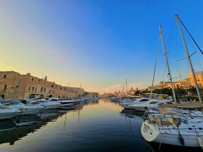 Una marina con imbarcazioni ormeggiate, edifici lungo il lungomare e cielo sereno.