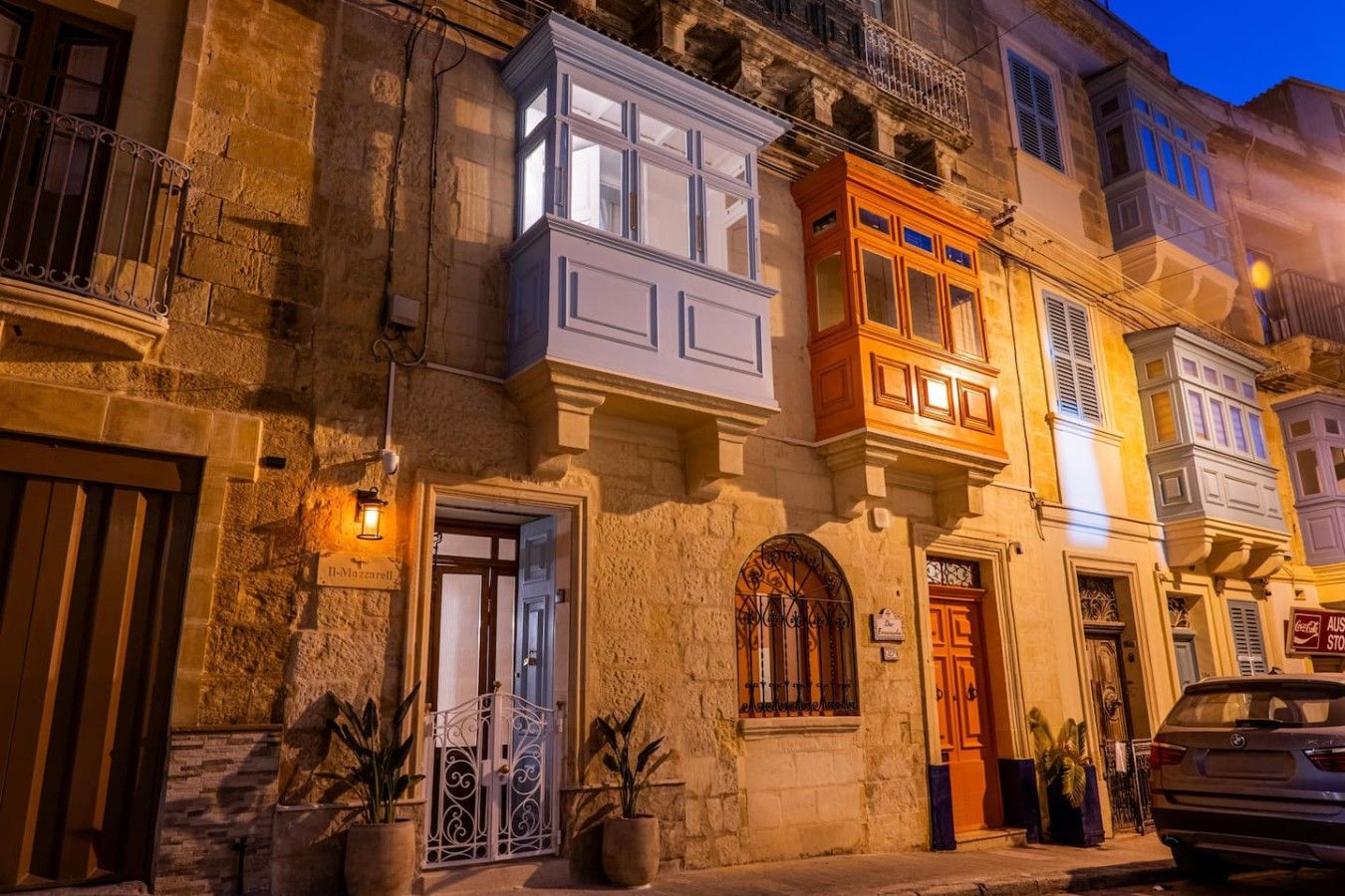 Un edificio storico con facciata in pietra, una porta in legno e un balcone con ringhiera in ferro battuto.