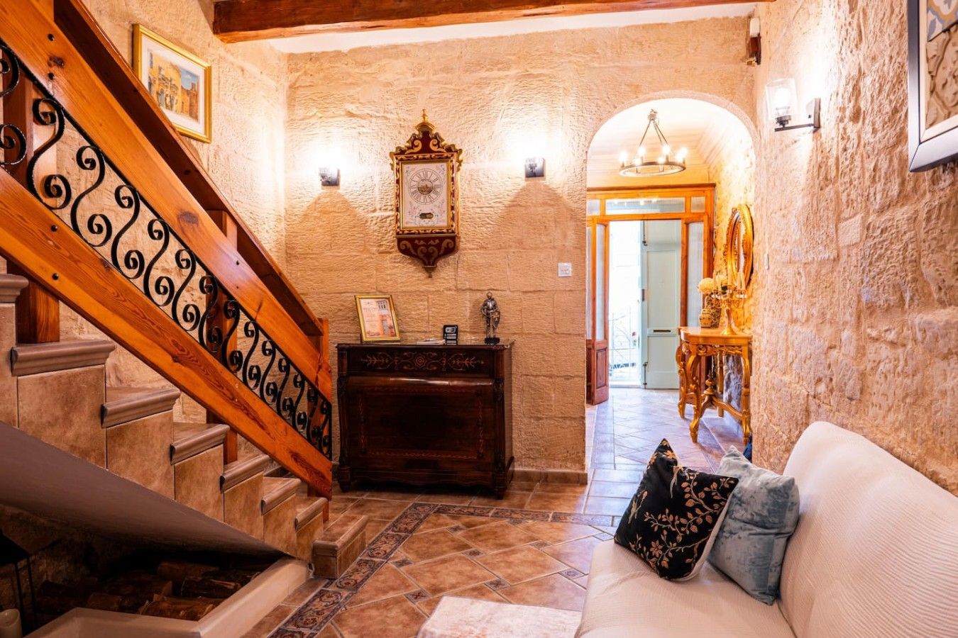 Una scala con ringhiere elaborate che conduce a una stanza con una panca di legno e un orologio a parete.