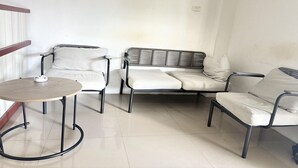 Una zona de estar con una mesa redonda, dos sillones y un sofá.