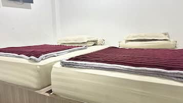 A hotel room with two beds, each with a red blanket and a pillow.