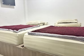 Habitación de hotel con dos camas, cada una con una manta roja y una almohada.