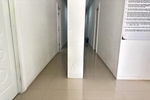 Un corridoio con pavimento piastrellato che conduce a una porta in fondo.