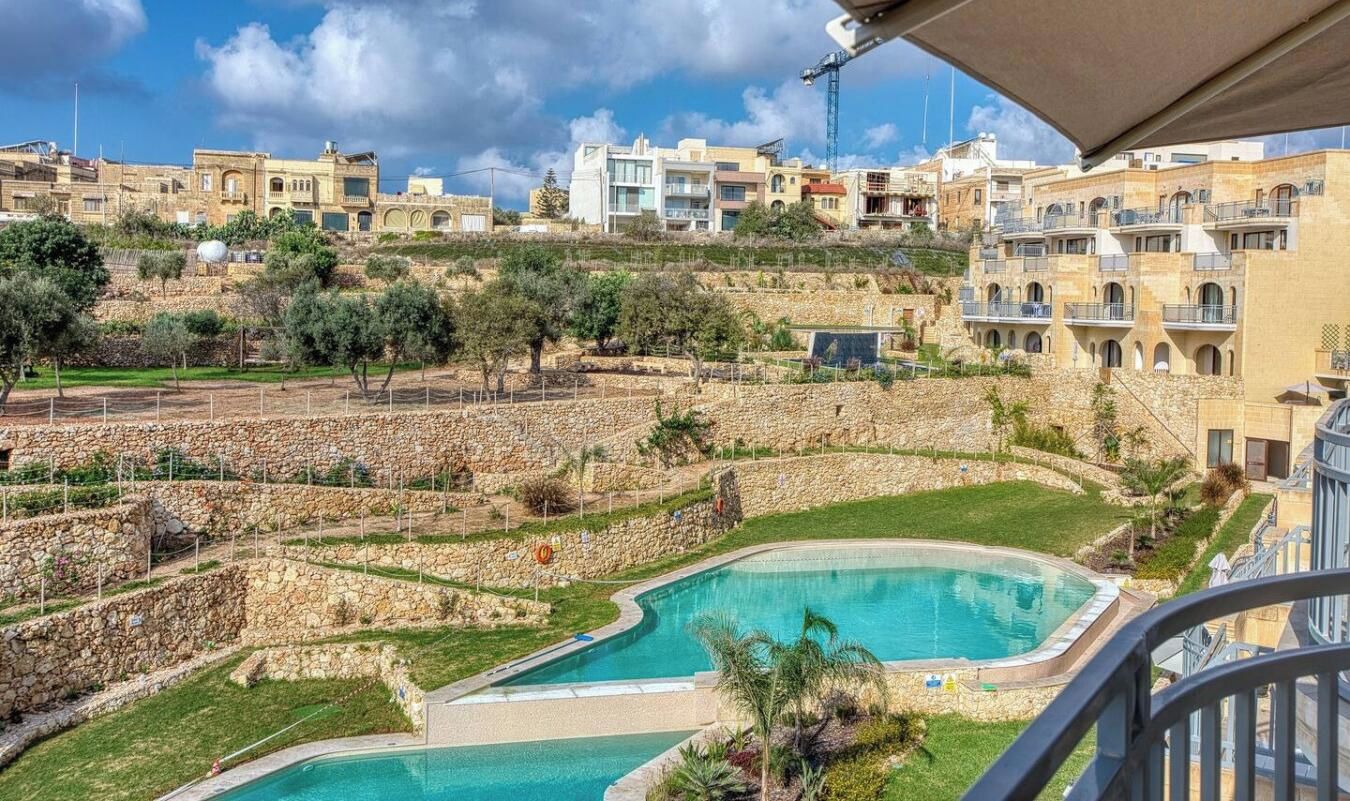 A residential area with a swimming pool, stone walls, and buildings in the background.