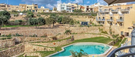 A residential area with a swimming pool, stone walls, and buildings in the background.