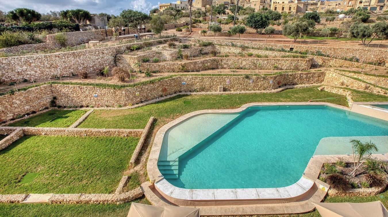 A swimming pool with stone walls and a grassy area.