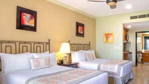 A hotel room with two beds, a ceiling fan, artwork on the walls, and a kitchenette area. - Beachfront Cabo Escape at Villa del Arco with Pools, Spa & Walkable Location (Cabo San Lucas)