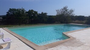 A rectangular swimming pool with clear blue water, surrounded by a tiled deck.
