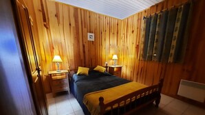 Una habitación con paneles de madera, una cama, dos mesitas de noche con lámparas y un radiador.