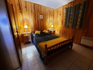 Een kamer met houten lambrisering, een bed, twee nachtkastjes met lampen en een radiator.