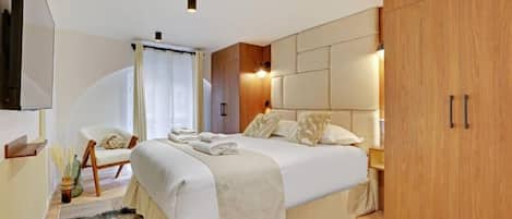 Un dormitorio moderno con una cama grande, un armario de madera, una silla y un televisor.