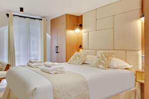 Ein Hotelzimmer mit einem großen Bett, einem Holzkopfteil, einem Nachttisch und einem Fenster mit Vorhängen.
