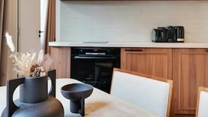 Une cuisine moderne avec une table à manger, une machine à café et un vase décoratif.
