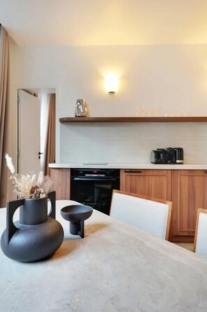 Una cocina moderna con una mesa de comedor, una cafetera y un jarrón decorativo.