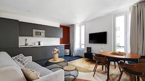 Un espace de vie moderne comprenant un canapé, une table à manger et un coin cuisine.