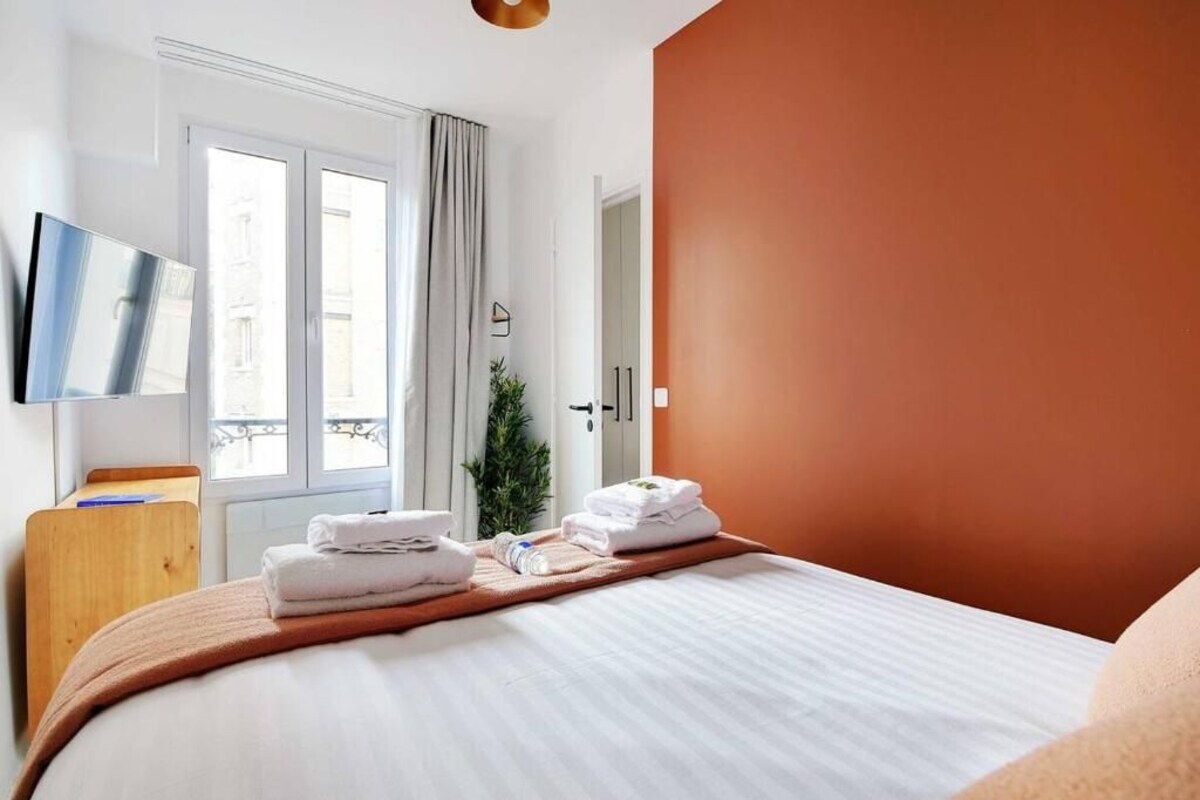 Habitación de hotel con una cama, televisor, puerta y ventana.
