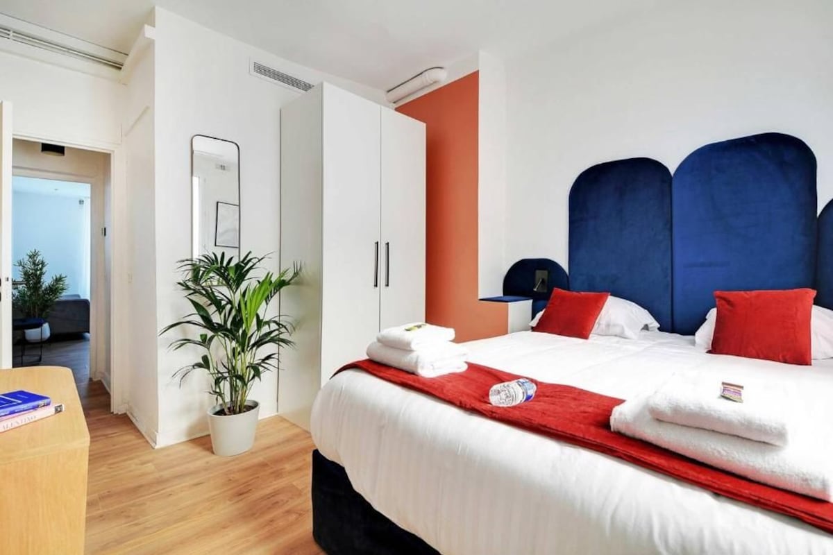 Una habitación de hotel con una cama, una planta en maceta, un escritorio y un armario.