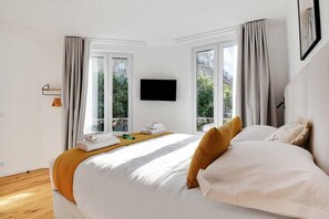 Une chambre d’hôtel avec un lit, un téléviseur à écran plat et une fenêtre avec des rideaux.