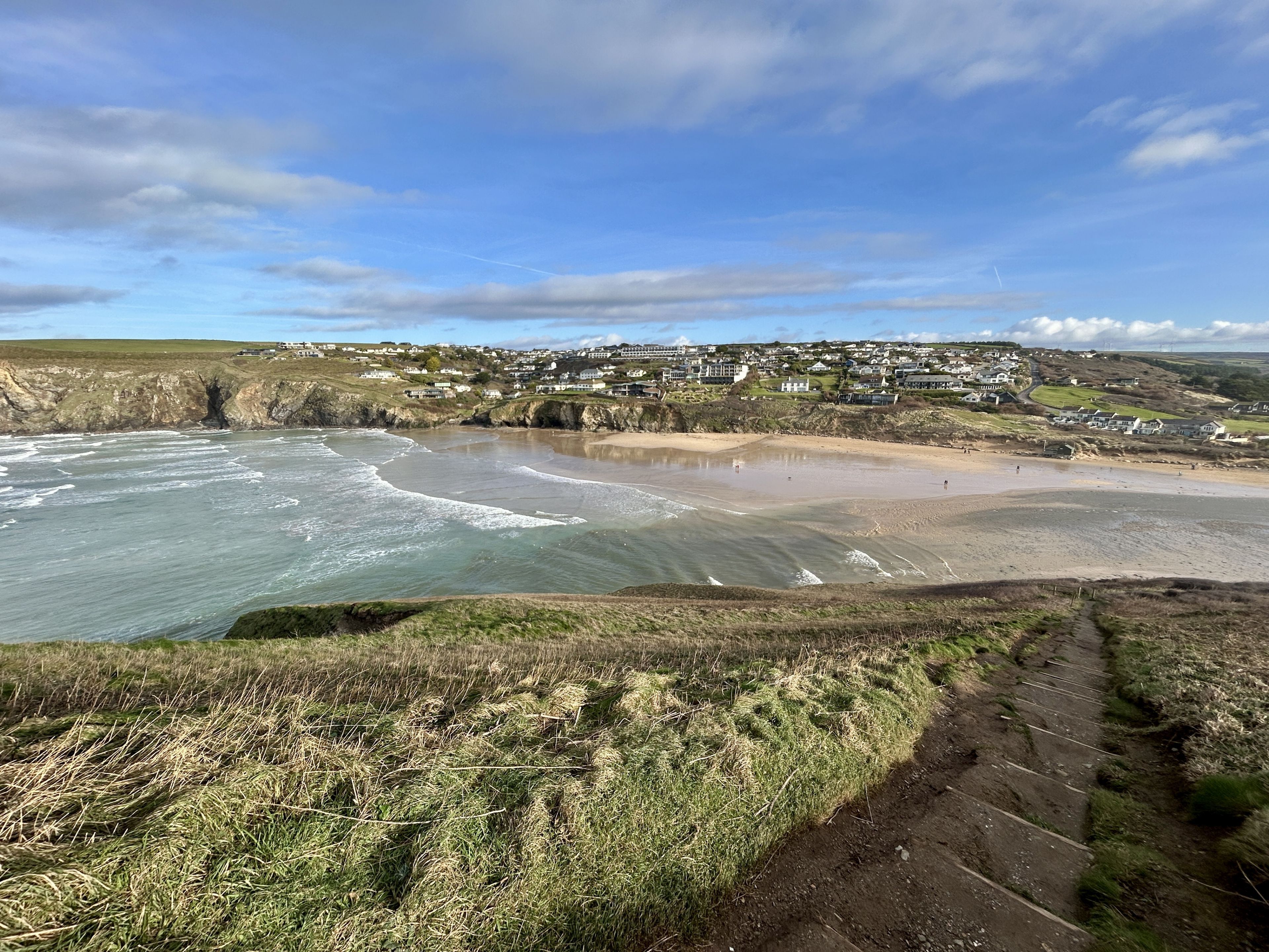 A coastal town with a beach, houses, and a clear sky.