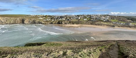 A coastal town with a beach, houses, and a clear sky.