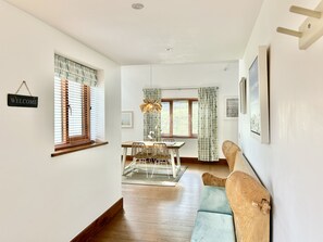 A modern interior with a dining area, a sofa, and a 'WELCOME' sign. - Spacious and secluded countryside escape - walking distance to Mawgan Porth Beach (Mawgan Porth)