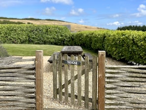 A wooden gate with a sign reading 'TREVONE' leading to a picnic area with benches. - Spacious and secluded countryside escape - walking distance to Mawgan Porth Beach (Mawgan Porth)
