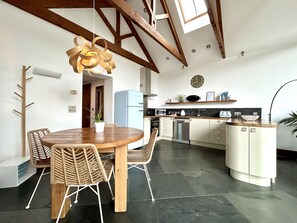A modern kitchen with a dining area, featuring a wooden ceiling, a round dining table with chairs, and a built-in dishwasher. - Countryside Cottage - 15 mins walk to Mawgan Porth Beach (Mawgan Porth)