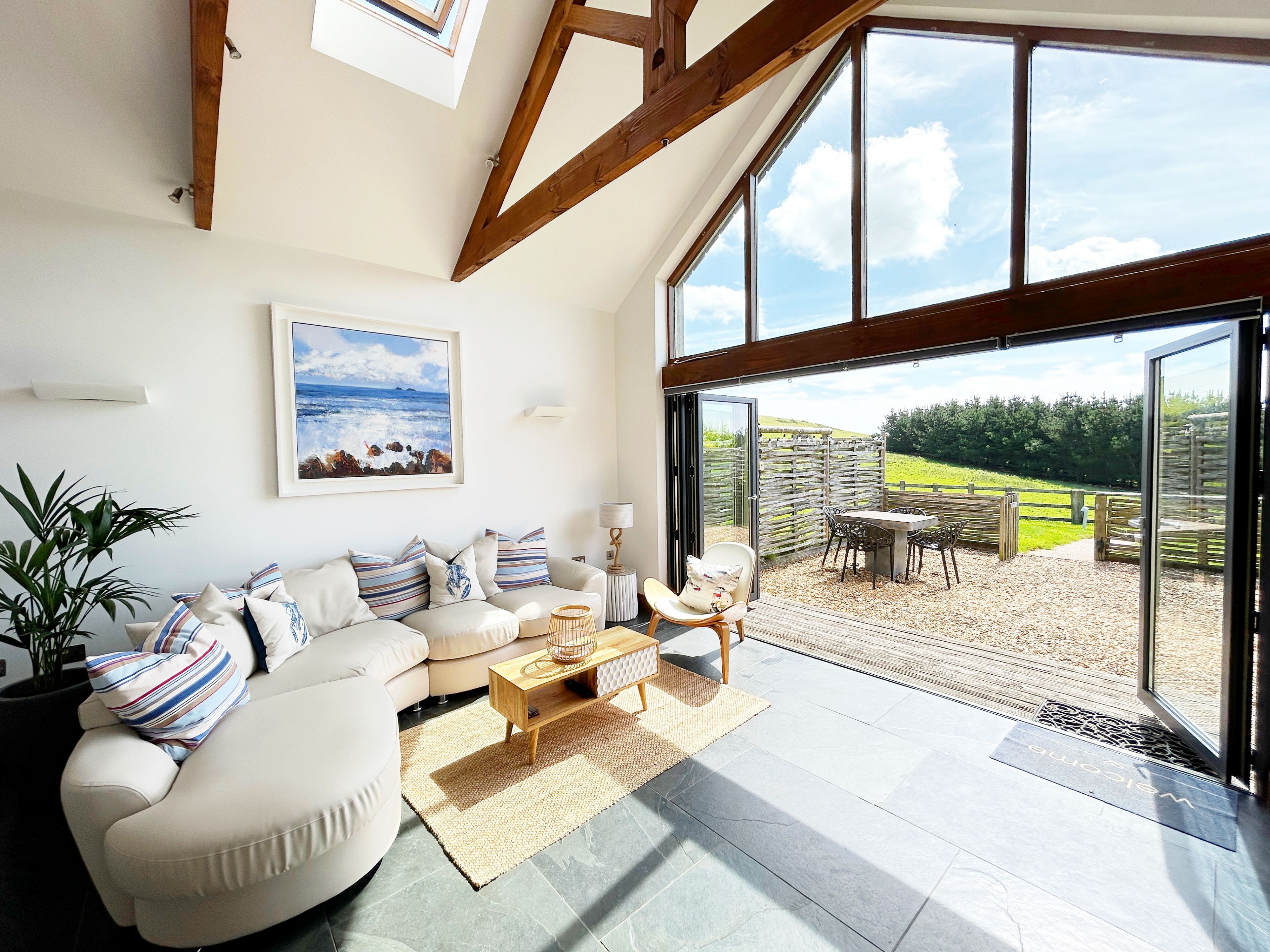 A spacious living room with a large window, a sofa set, a coffee table, and a view of the outdoors.