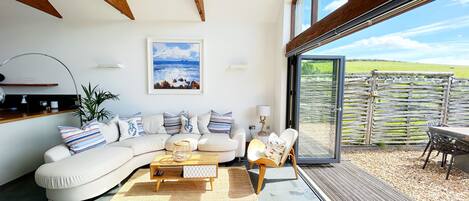 A modern living room with a large window, a sofa set, a coffee table, and a view of the outdoors.
