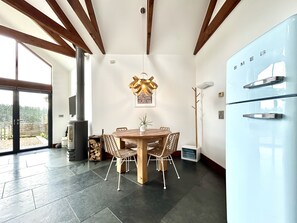 A modern kitchen with a round wooden table, built-in appliances, and a view to the outside. - Countryside Cottage - 15 mins walk to Mawgan Porth Beach (Mawgan Porth)