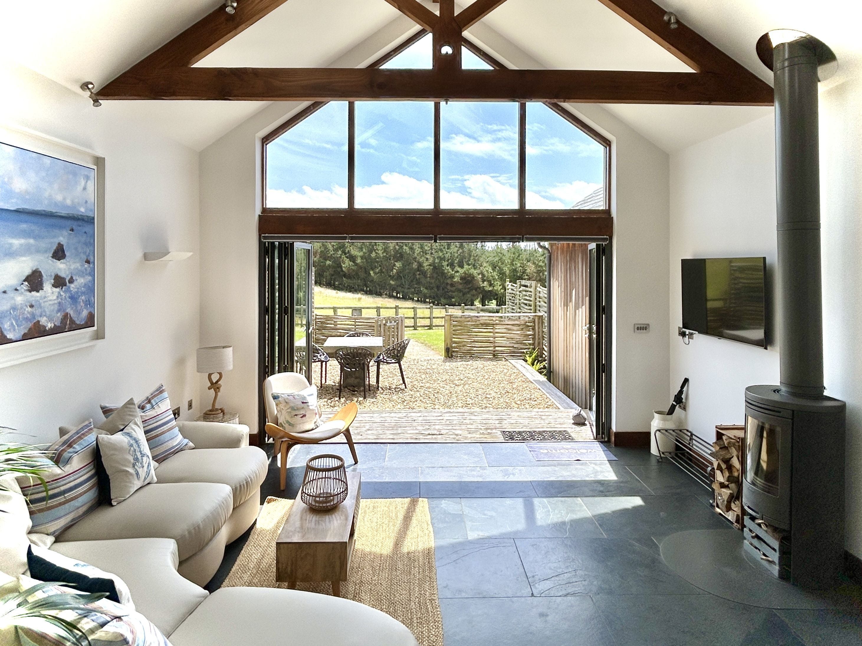 A spacious living area with a high ceiling, a fireplace, a sofa set, and a view of the outdoors.