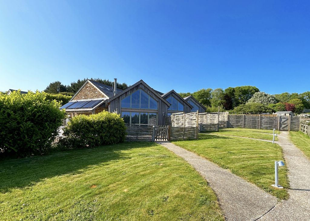 A house with a paved driveway, a wooden fence, and a well-maintained lawn.