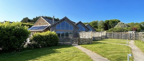 A house with a paved driveway, a wooden fence, and a well-maintained lawn.