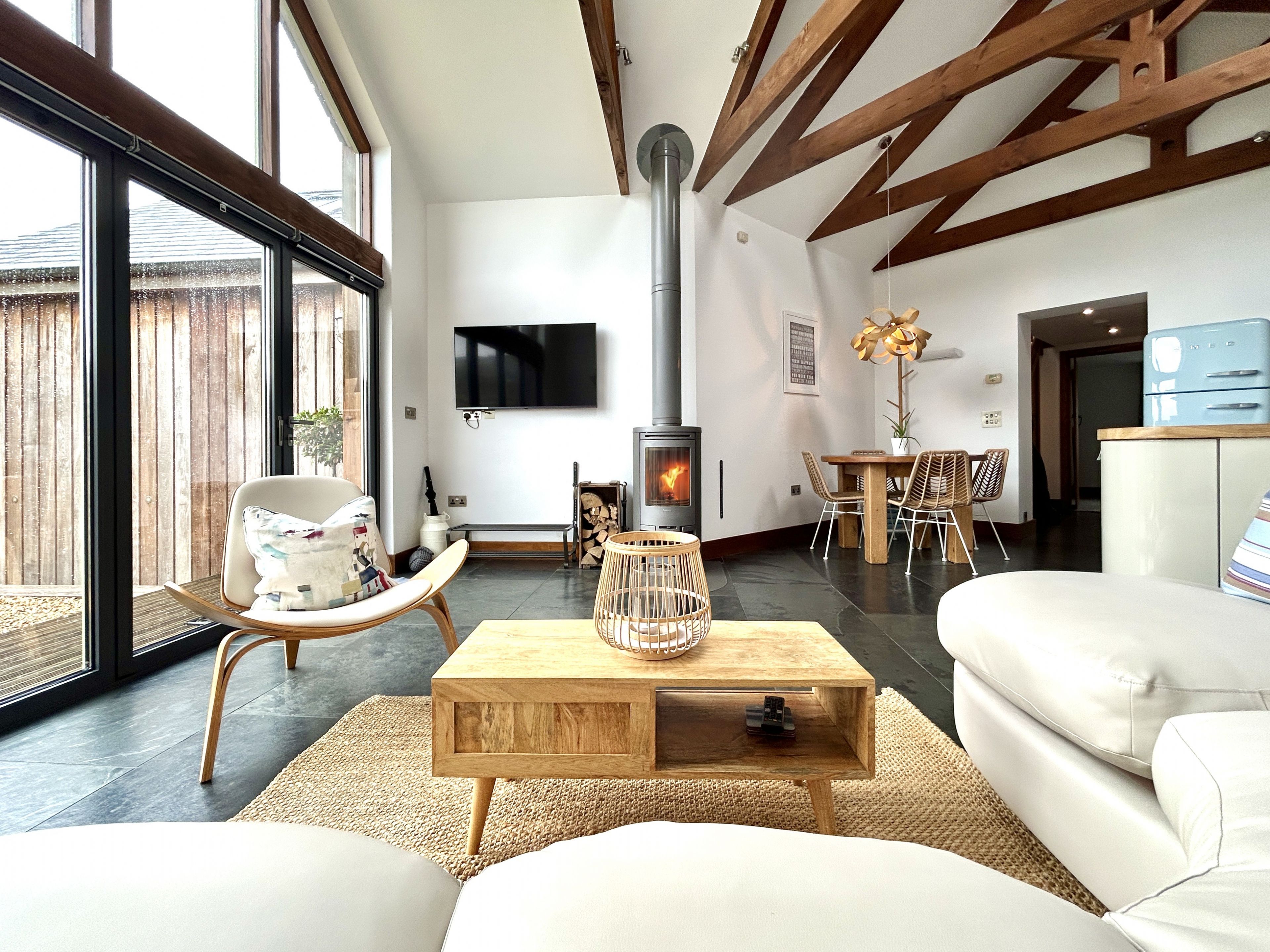 A modern living room with a fireplace, large windows, and a dining area.