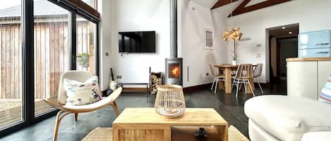 Ein modernes Wohnzimmer mit Kamin, großen Fenstern und einem Essbereich.