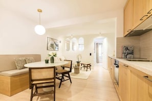 A modern kitchen with wooden cabinets, a dining area with a round table and chairs, and a visible kitchen island. - Opéra - Elégant appartement - Haystia (Paris)