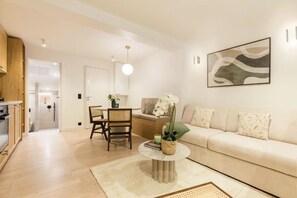 A modern living room with a sofa, a dining table, chairs, and a coffee table. - Opéra - Elégant appartement - Haystia (Paris)