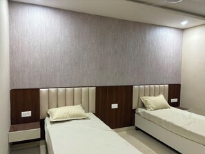 A room with two beds, each with a headboard and a nightstand.