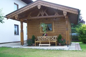Uma cabana de madeira com varanda, um banco e plantas em vasos.