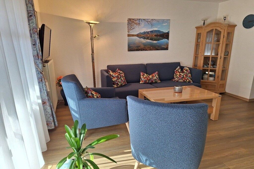 A living room with a sofa set, a coffee table, a lamp, a cabinet, and a painting on the wall.