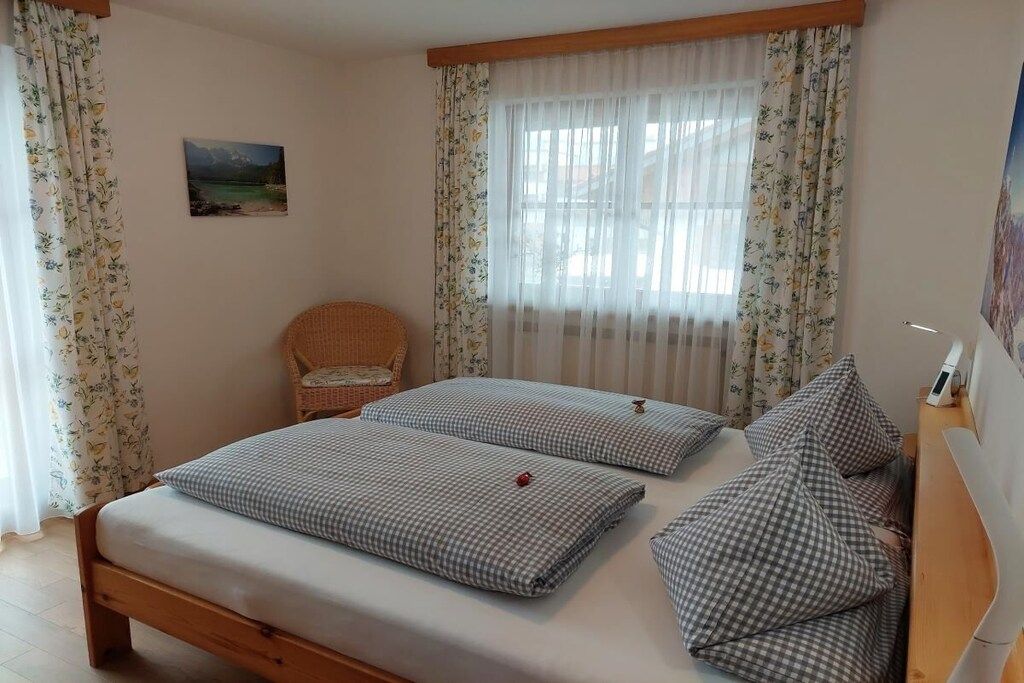 A bedroom with two beds, a chair, and a painting on the wall.