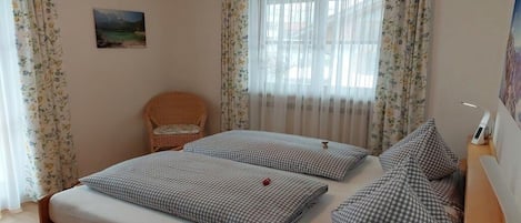 Une chambre avec deux lits, une chaise et un tableau au mur.